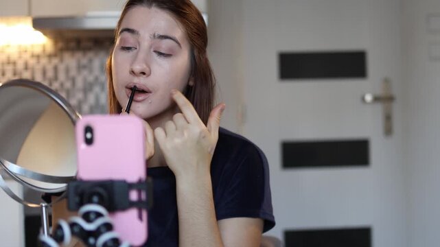  Makeup artist films a simple lip makeup tutorial showing how to outline and fill lips on camera focusing on technique and sharing tips while working close to the mirror