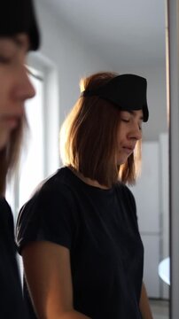 Vertical screen Sleepy woman stares at her reflection wanting to fix her tired face but gives up with a quiet sigh deciding to leave everything as it is lacking energy to do anything this morning