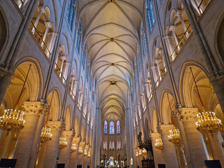 Paris, France - December 10, 2025: The interior of Notre-Dame Cathedral after restoration. View up toward the soaring vaulted ceiling. Golden chandeliers and stained glass windows line the nave