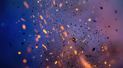 Close-up generic sparks and burning debris in fiery explosion with dynamic movement against a blue background