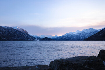 Snowy mountains and fjord landscape in Norway. Snow covered forest road in Norway during winter.