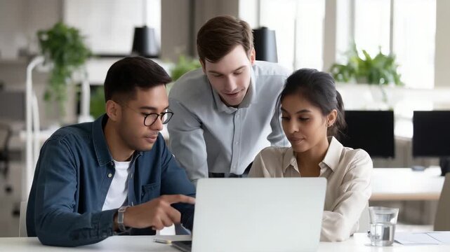 three diverse coworkers collaborating in a modern office two men and one woman sitting at a white desk with a laptop
