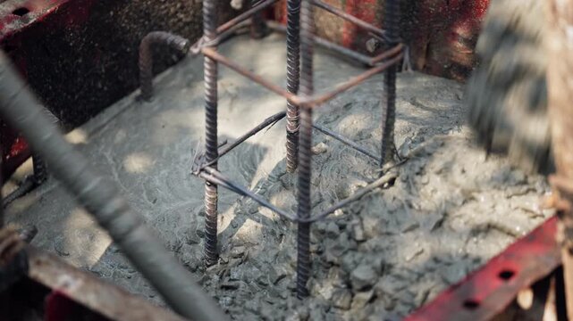 Wet concrete being poured into a reinforced steel rebar base, essential step in foundation construction, civil engineering concept.
