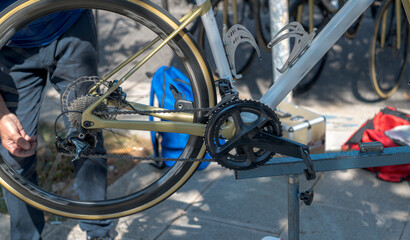 Professional road bike maintenance on a repair stand. Close-up of the drivetrain, chain, and derailleur with a spinning rear wheel showing motion blur. Focus on high-end bicycle components.