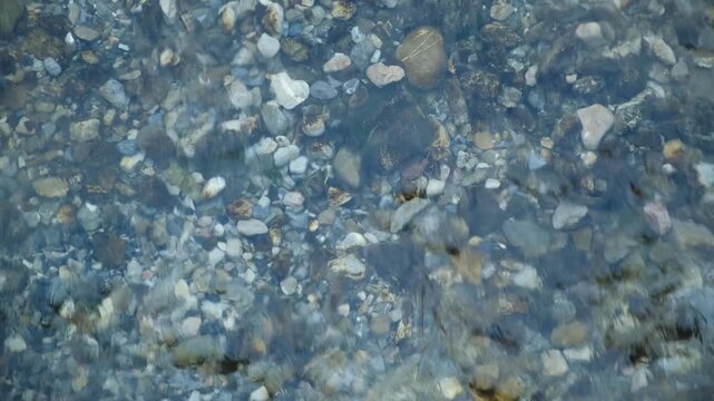 Rapid stream of cold river water with ripples top view. Crystal clear mountain stream flow in snowy winter season