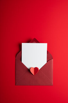 Love letter envelope with red paper craft hearts on red background. White paper with space for text. Valentines day, 14 February. Love and romance theme.