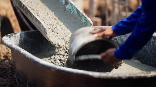Concrete mix flows from chute into column foundation with rebar reinforcement, civil construction progress at open air site.