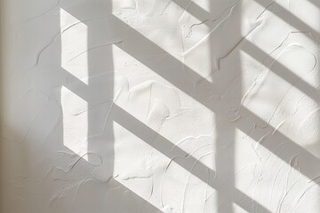 Fototapeta premium Soft diffused sunlight passes through a window and casts diagonal shadows on a plain wall. The scene shows a workspace bathed in light, creating contrast on the textured surface
