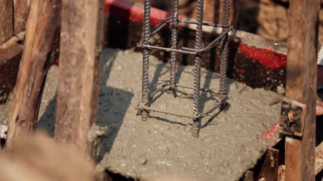Close-up image of concrete pouring over steel rebar during construction of reinforced building foundation in civil engineering site.