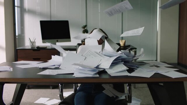 Frustrated office worker buried under pile of document. Overwhelmed employee experiencing burnout at workplace. Panning and tilting camera movement.