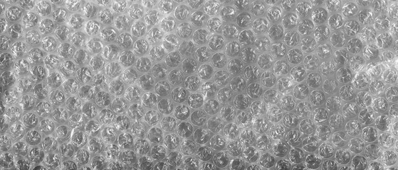 Transparent bubble wrap texture with soft reflected light. Plastic packaging material background, protective wrapping surface, abstract pattern, close up.