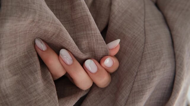 A beautiful feminine manicure in a milky shade with silver stripes. Autumn design.