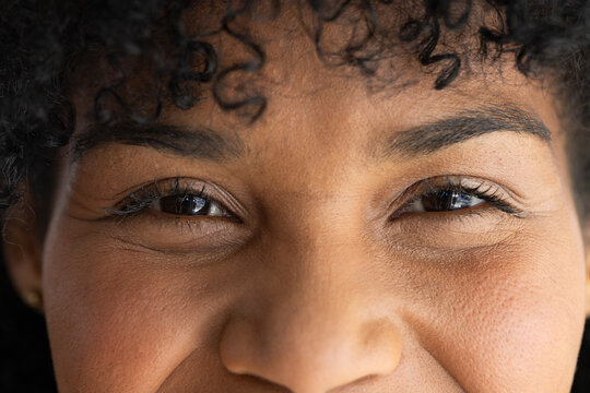 African American woman smiling with eyes squinted in close-up studio showing gold stud earring