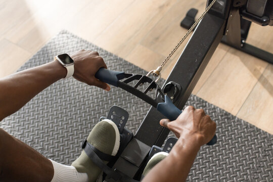 V-bar and metal chain are being gripped on rowing machine at home gym over rubber mat