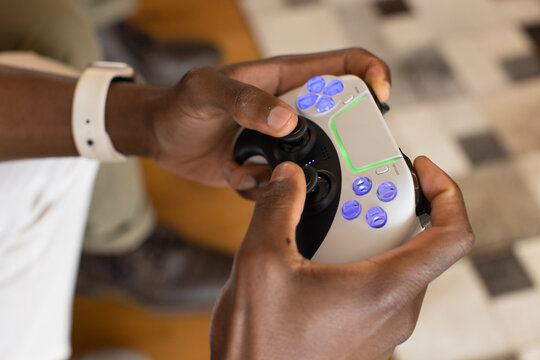 African American male wearing white wristband holding white controller with green light at home