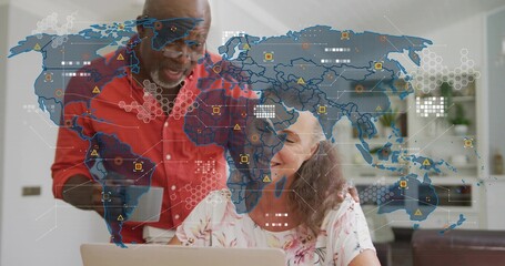 Pointing man redshirt guiding woman floral-top using laptop in kitchen, with digital map and mug