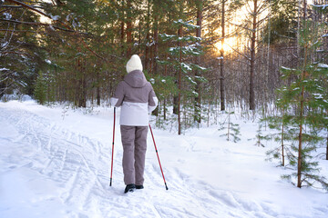 Woman in winter park with Nordic walking poles