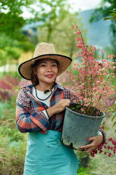Woman Holding Potted Plant in Garden