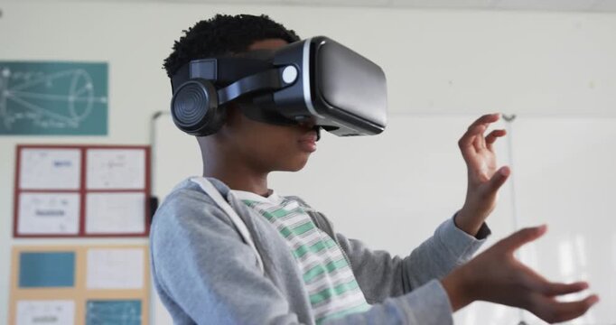 Headset activating, African American teen reaching, pinching, exploring virtual scene in class
