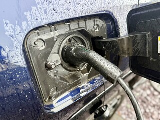 Electric car charging with a power cable connected to the vehicle charging port. Close-up view of an electric vehicle during charging, highlighting modern transportation, sustainable mobility, and cle