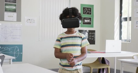 African American child entering classroom wearing VR headset, reaching and tapping during VR lesson