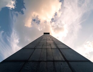 Low-angle view of a tall, dark structure reaching towards the cloudy sky