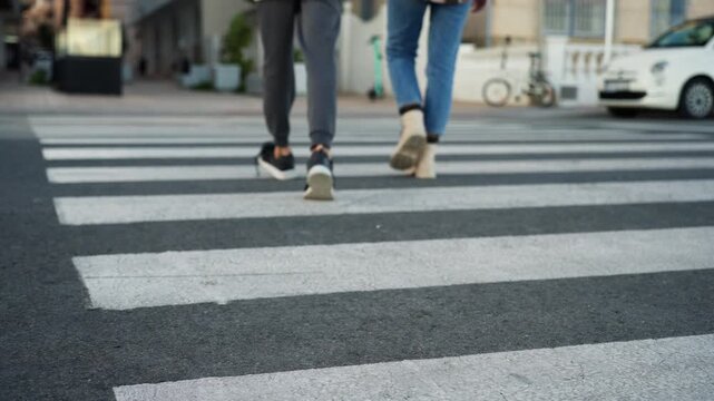 Close up  mother and teenage son crossing street on zebra crossing, walking away from camera. Family spending quality time together, walking in city