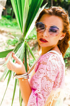 Beautiful lady in a swimsuit and colorful parasol against the background of the sea, on a tropical island, walk on the coast, sitting on a hammock, summer mood