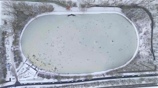 Top down aerial video of people ice skating on frozen lake