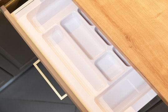 Open kitchen drawer with white plastic cutlery organizer.