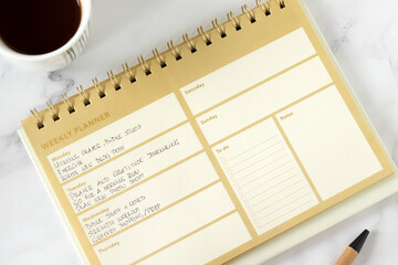 Christian to do list in weekly planner notebook with coffee cup. Top view.
