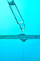 Dropper dispensing liquid into blue water surface