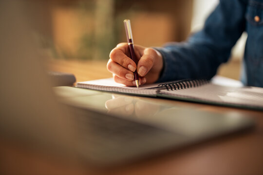 Person writing notes in spiral notebook with pen