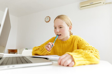 Teenage girl studying at home using laptop, student thinking while doing homework, child holding pen, online learning, education concept, focus and concentration,