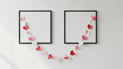 A romantic decoration of paper hearts hanging between two empty black frames on a white wall