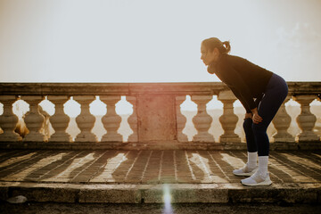Woman exercises outdoors in Malta during sunrise near a stone railing