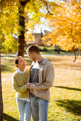 Couple enjoys a sunny day in the park surrounded by vibrant autumn leaves