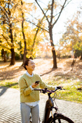 Korean woman enjoys a sunny day on her bike in a vibrant autumn park