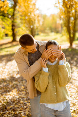 Playful couple enjoying a sunny autumn day in a beautiful park filled with colorful leaves