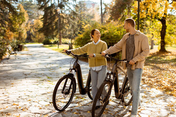 Couple enjoys a lovely autumn day biking in a serene park filled with colorful leaves