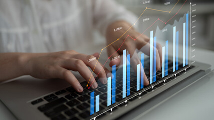 Focus on hands typing on a laptop with financial graphs and analytics, showcasing a modern workspace environment relevant to business and technology growth. Scalp