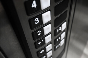 Elevator control panel closeup with numbered buttons. Modern lift interior detail. Vertical keypad with floor selection. Urban building transportation technology background.