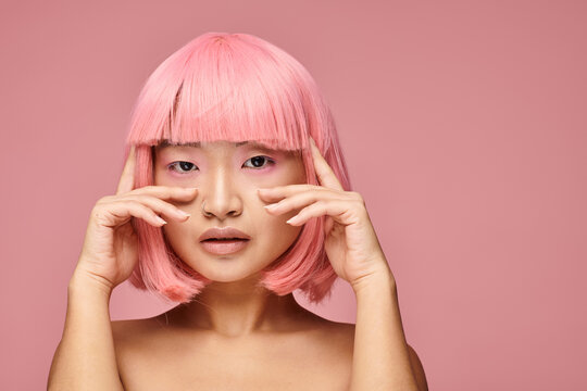 Young woman with pink hair exudes elegance and charm against a soft pink background