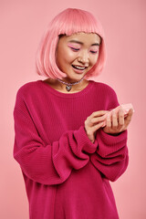 Joyful moment of a young woman in a vibrant pink sweater against a soft pink backdrop
