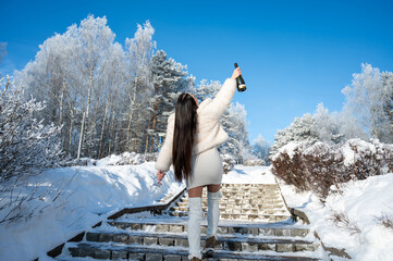 Elegant woman celebrating winter holidays with champagne outdoors in snowy park stairs