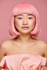 Young woman with pink hair exuding beauty and style against a soft pink backdrop