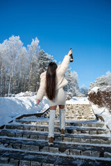 Elegant woman celebrating winter holidays with champagne outdoors in snowy park stairs