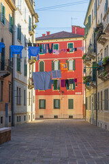 Fototapeta premium Venetian street with hanging laundry and Saint Marks flag