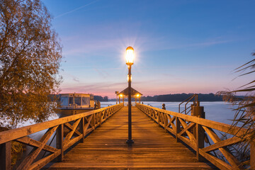 Obraz premium Steg am See in Neuruppin mit Aussichtsplattform am Ende bei Sonnenaufgang im Herbst