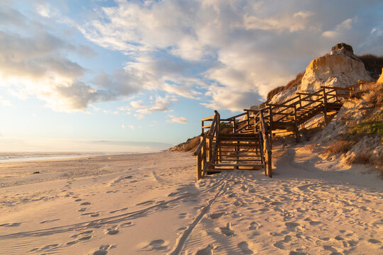 Scenic wooden boardwalk on Cuesta Maneli Beach, Huelva, Spain. Natural coastal landscape, golden sand, cliffs and sunset light, ideal for travel, nature and sustainability concepts.